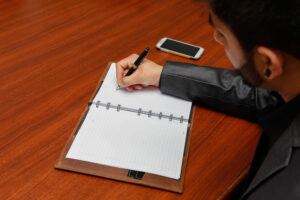 Man Writing Notes with Smartphone on the Table (1)